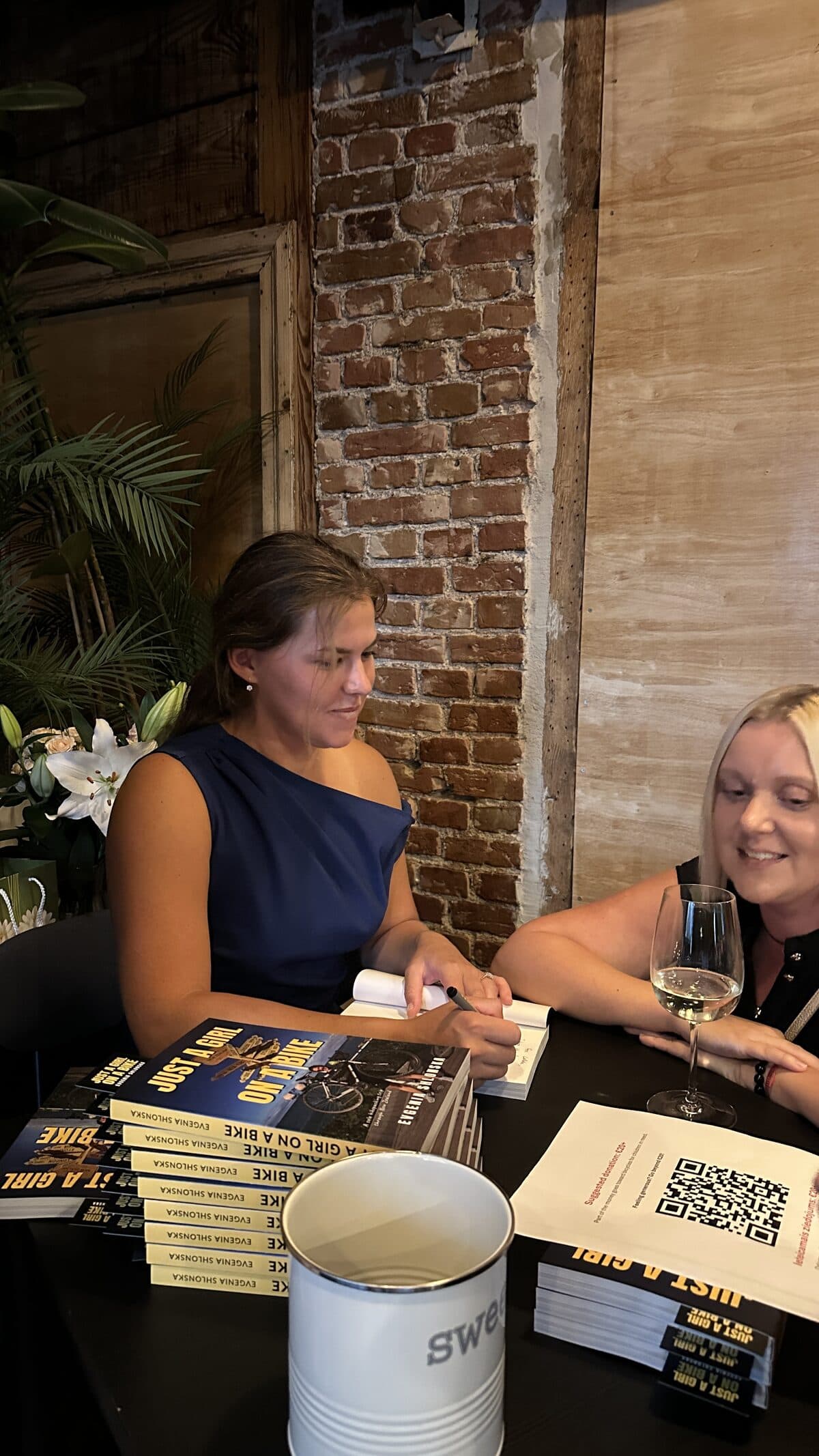 Evgenia at the signing table, talking with a guest