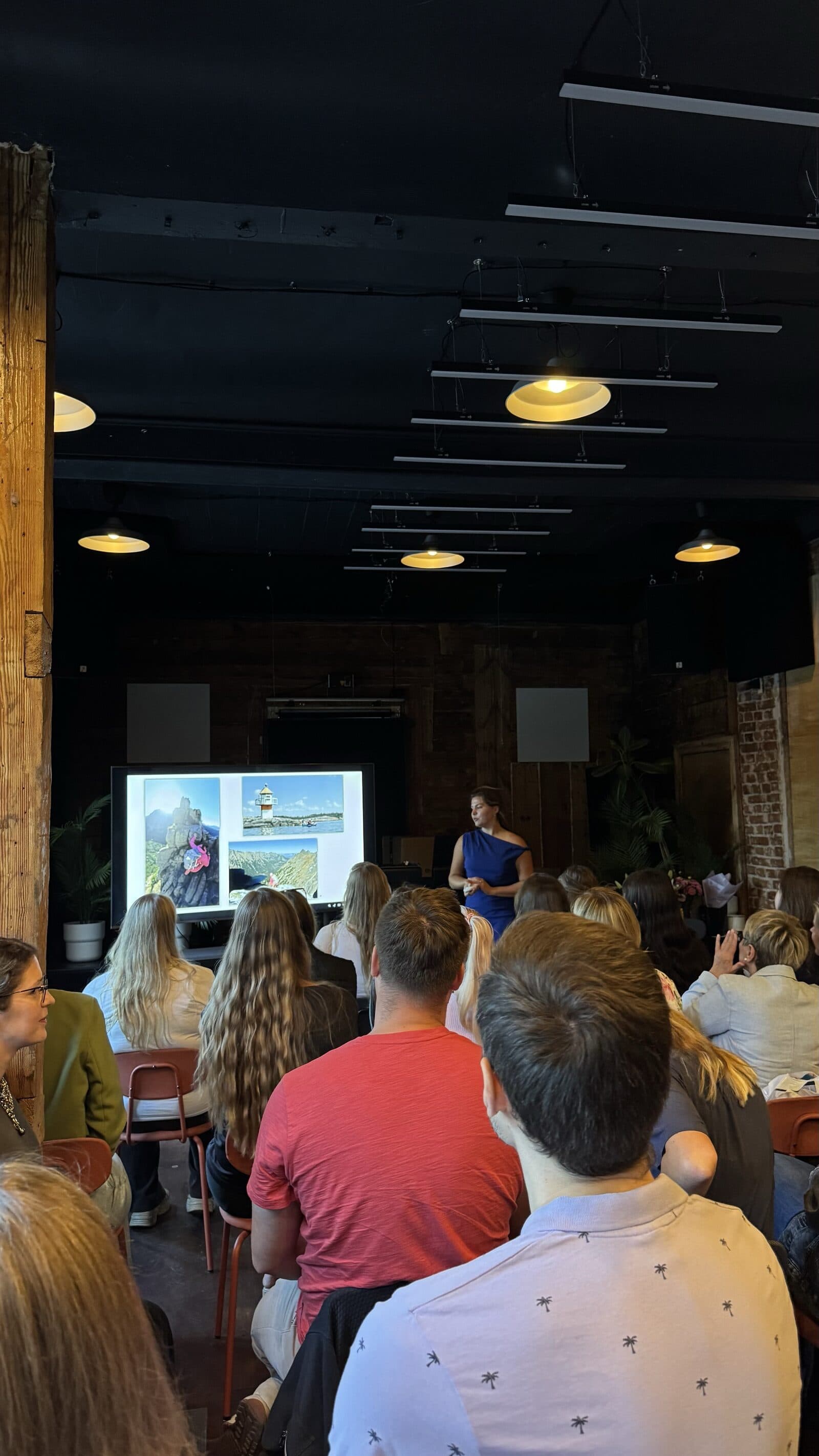Evgenia speaking to a full room, photos from the route on the screen behind her