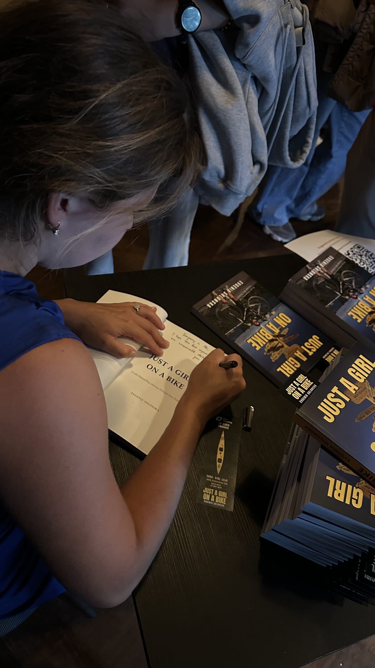 Evgenia signing a copy of the book at the table